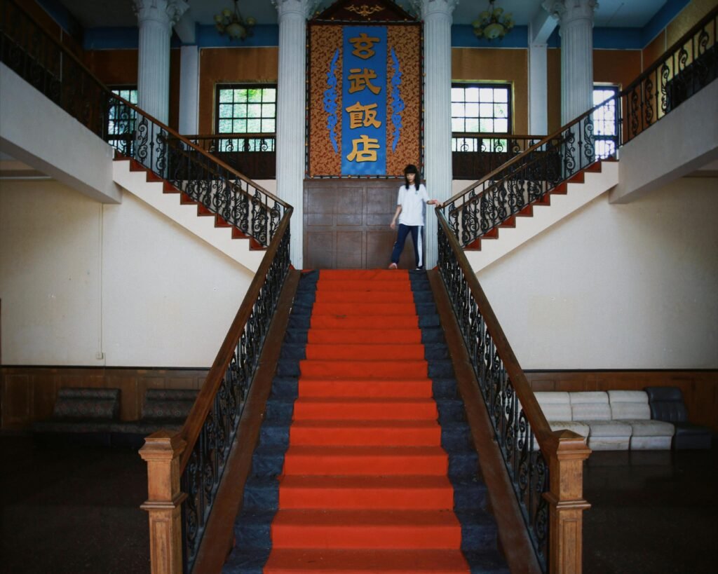Symmetrical staircase with red carpet and Chinese script in a grand hall interior.